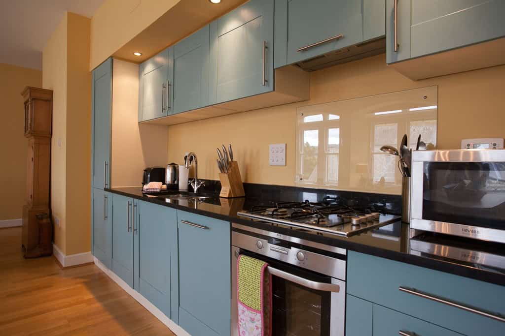 Modern blue kitchen with appliances, black countertop, and wooden flooring at Highland Club Scotland.