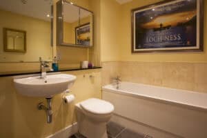 Bathroom with bathtub, sink, and mirror at Highland Club Scotland.