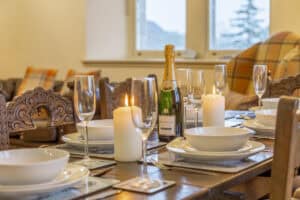 Elegant dining table with candles, champagne, and glassware in Highland Scotland.