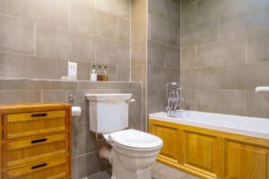 Bathroom with bathtub, toilet, and wooden storage in Highland Club Scotland.