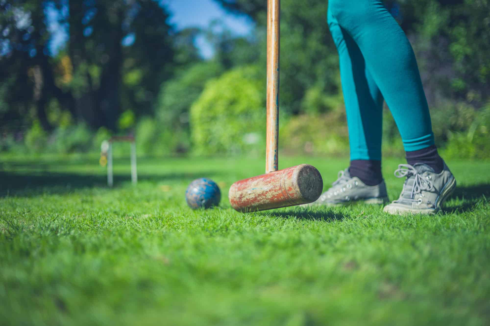 Person playing croquet on lush green lawn at Highland Club Scotland.
