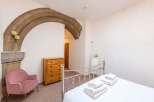 Bedroom with historic stone arch and modern furnishings.