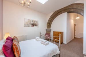 Spacious bedroom featuring an exposed stone arch, white walls, and simple furnishings for a comforta.