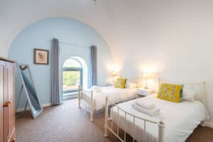 Bright Highland Club guest room with two single beds and scenic window view.