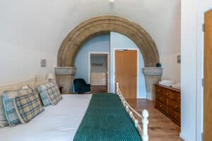 Elegant bedroom featuring a stone archway and contemporary decor at Highland Club Scotland.