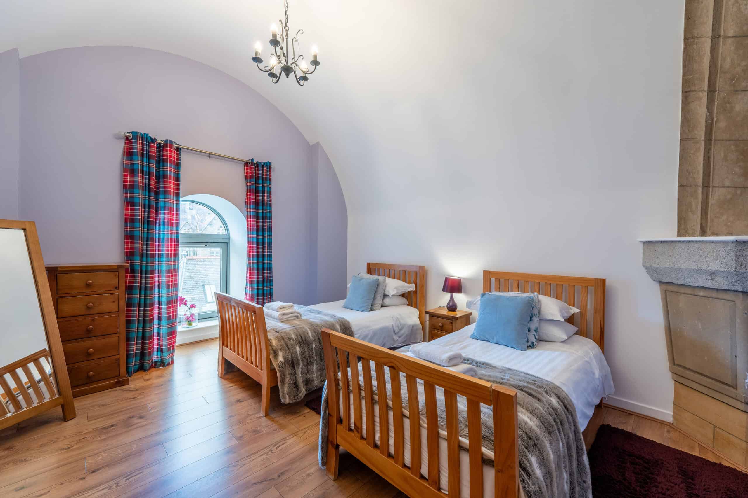 Bright Highland Club bedroom with twin beds and Scottish tartan curtains.