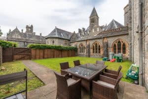 Outdoor seating area at Highland Club Scotland with garden and historic stone buildings.