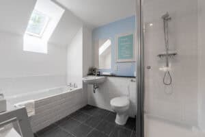Bright bathroom featuring skylight, walk-in shower, and contemporary fixtures at Highland Club Scotl.