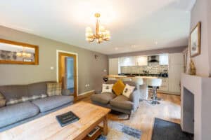 Highland Club Scotland living room with contemporary furniture and open-plan kitchen.