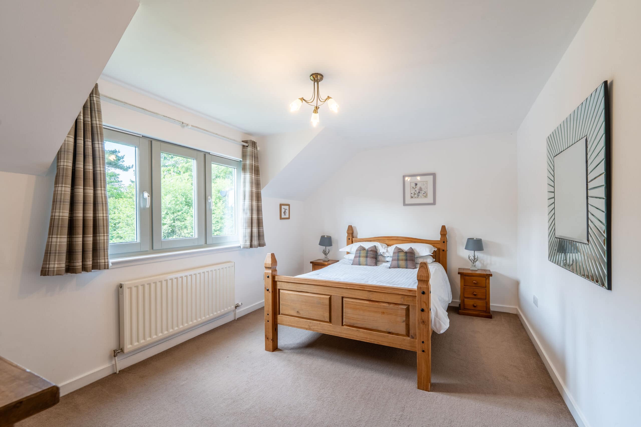 Bright bedroom with wooden bed and large window, offering scenic views and modern comfort at Highlan.
