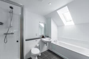 Bright bathroom featuring a skylight, bathtub, and shower at Highland Club Scotland.