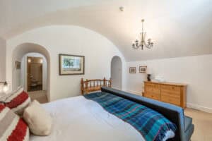 Comfortable bedroom with a large bed, wooden furniture, and elegant chandelier in Highland Club Scot.