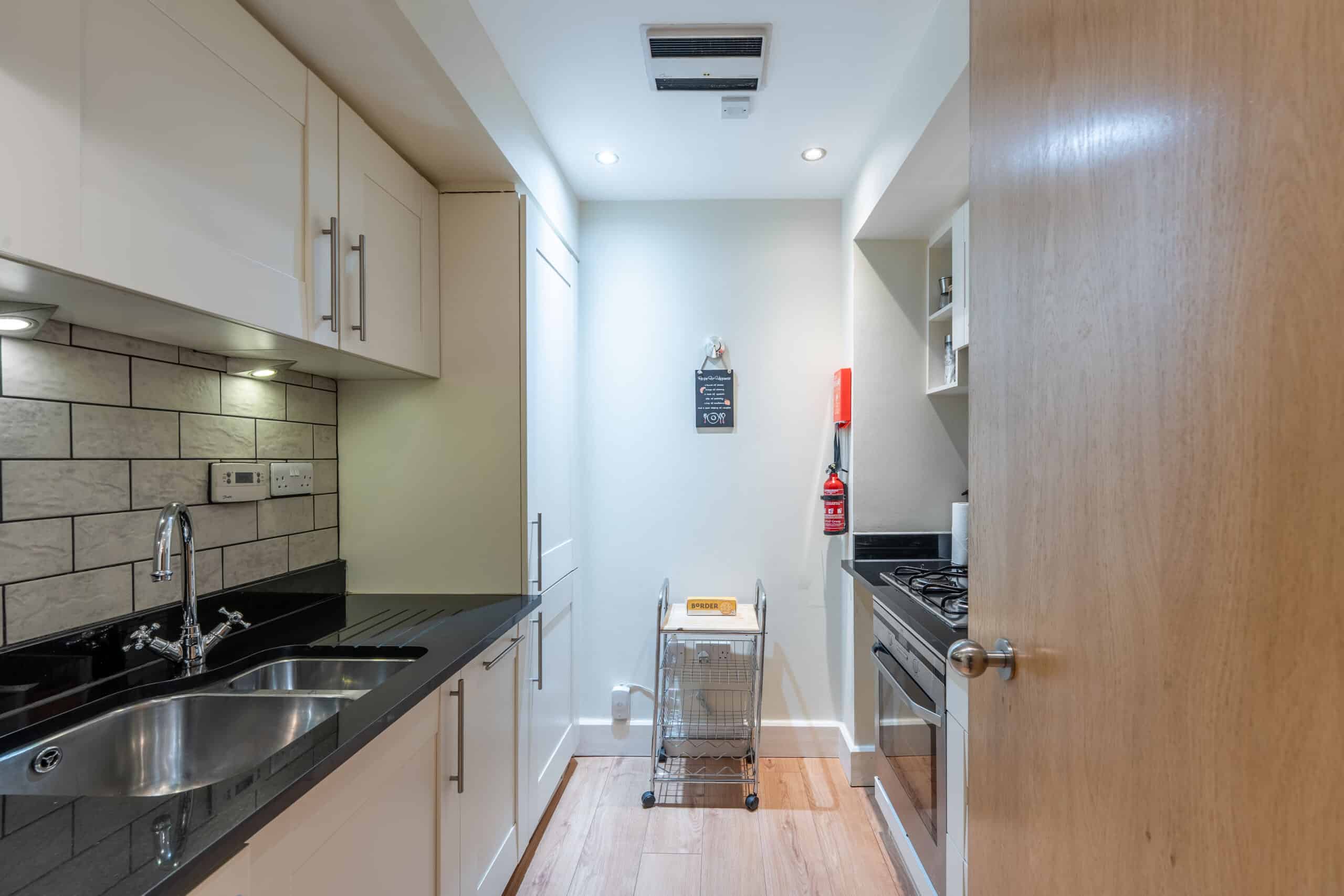 Modern kitchen with sleek white cabinets and black countertops at Highland Club Scotland.