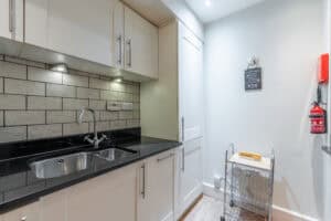 Modern kitchen with white cabinets, black countertop, and tiled backsplash.