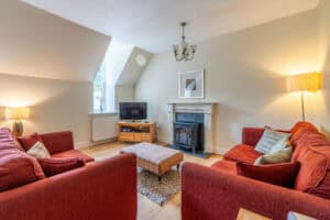 Cosy living room with red sofas, fireplace, and TV in Highland Club Scotland development.