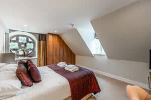 Comfortable bedroom with sloped ceilings and a large window at Highland Club Scotland.