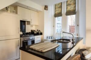 Modern kitchen with white cabinets and black countertops at Highland Club Scotland.