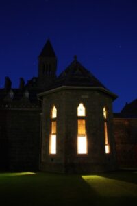 Historic Highland Club Scotland at night with illuminated windows and starry sky.