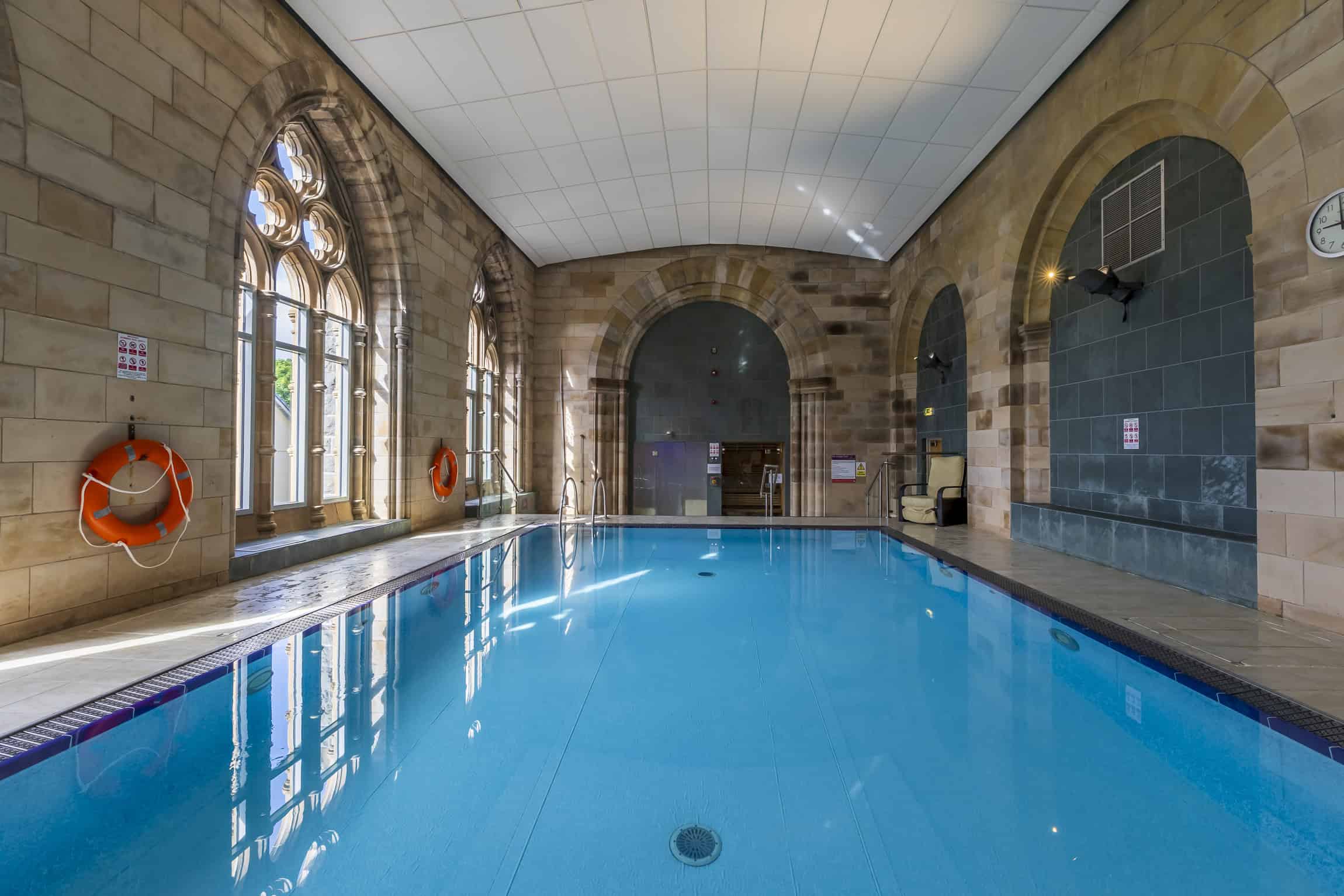 Indoor swimming pool at Highland Club Scotland, featuring historic architecture and modern amenities.