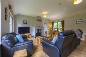 Comfortable living room with leather sofas, fireplace, and large windows overlooking scenic Highland.