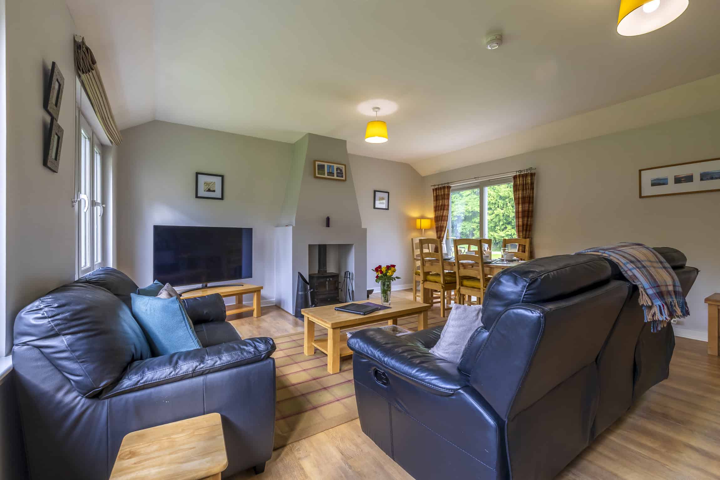 Comfortable living room with leather sofas, fireplace, and large windows overlooking scenic Highland.