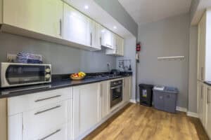 Modern kitchen with white cabinets and wooden flooring at HCS Development, Highland Club Scotland.