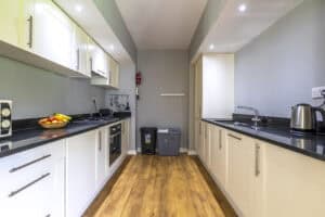 Modern kitchen with white cabinets and black countertops at Highland Club Scotland.