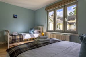 Bright bedroom with large window and cosy furnishings at Highland Club Scotland.