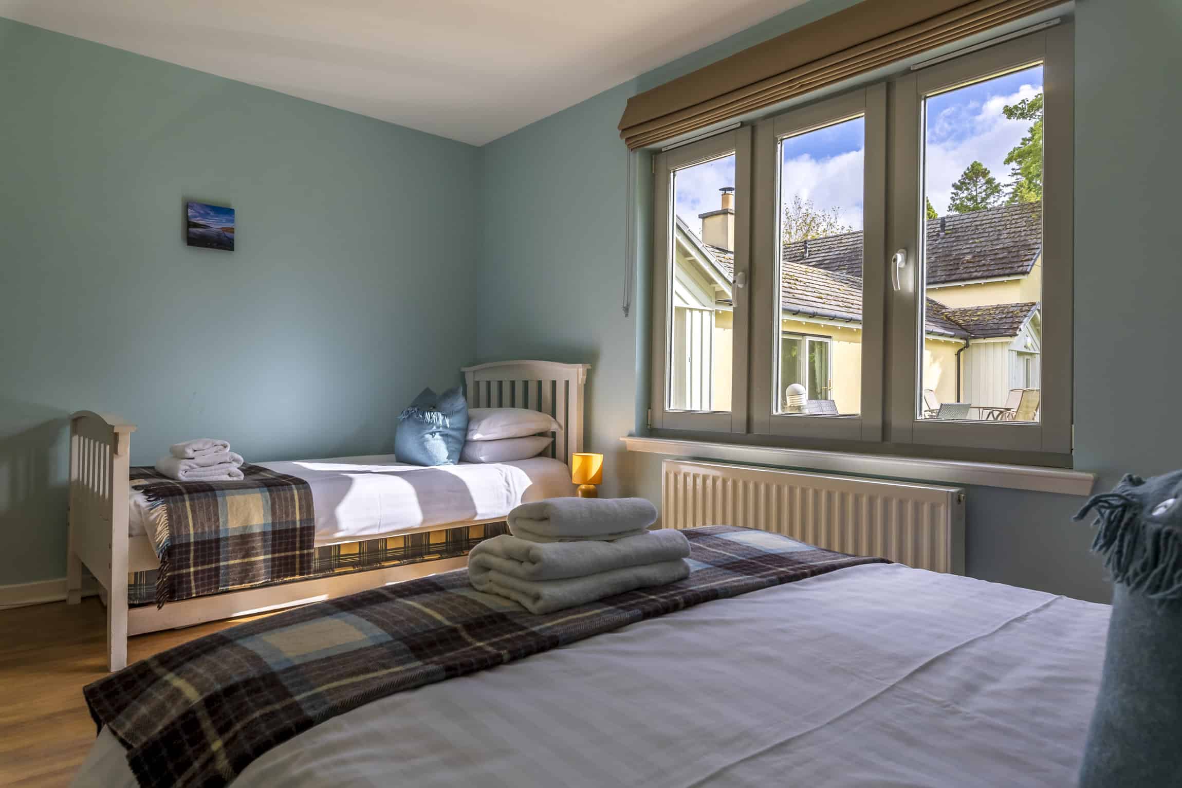 Bright bedroom with large window and cosy furnishings at Highland Club Scotland.