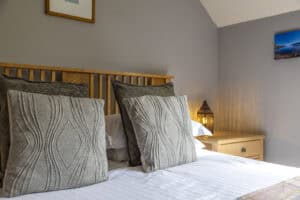Modern bedroom with wooden headboard and decorative cushions in Highland Club Scotland development.