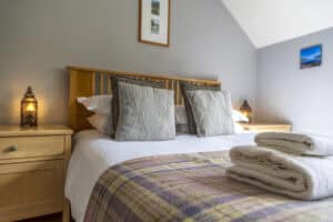 Modern bedroom with wooden furniture and cozy linens at Highland Club Scotland.