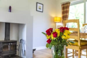 Red and yellow roses in a glass vase inside a bright living room.