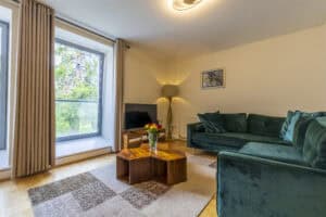 Modern living room with large window, green sofa, and wooden coffee table in Highland Club Scotland.