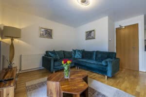Comfortable living room with teal velvet sofa and modern decor at Highland Club Scotland.