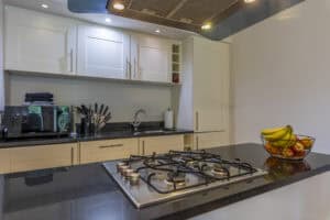 Modern kitchen with white cabinets and black countertop in Highland Club Scotland development.