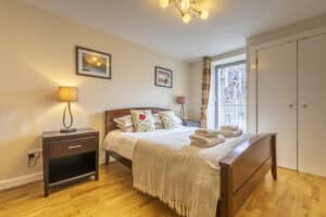 Modern bedroom with wooden furniture and cosy decor at Highland Club Scotland.