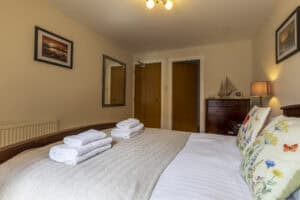 Comfortable bedroom with neatly made bed, decorative pillows, and wooden furniture in Highland Club.