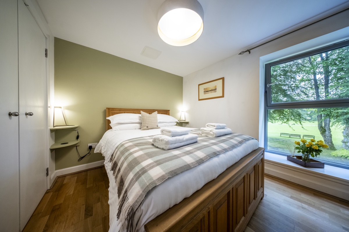 Cozy bedroom with large window overlooking greenery at Highland Club.