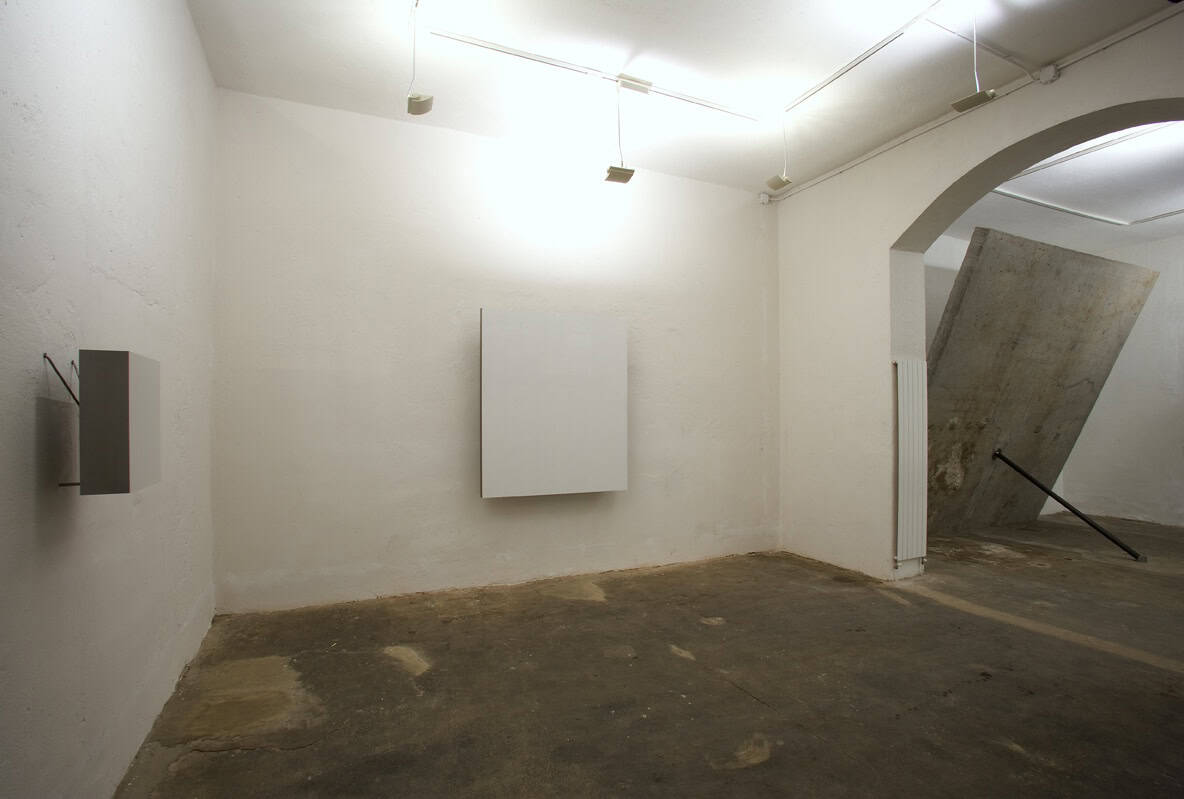 Minimalist art gallery interior with white walls and concrete floor.