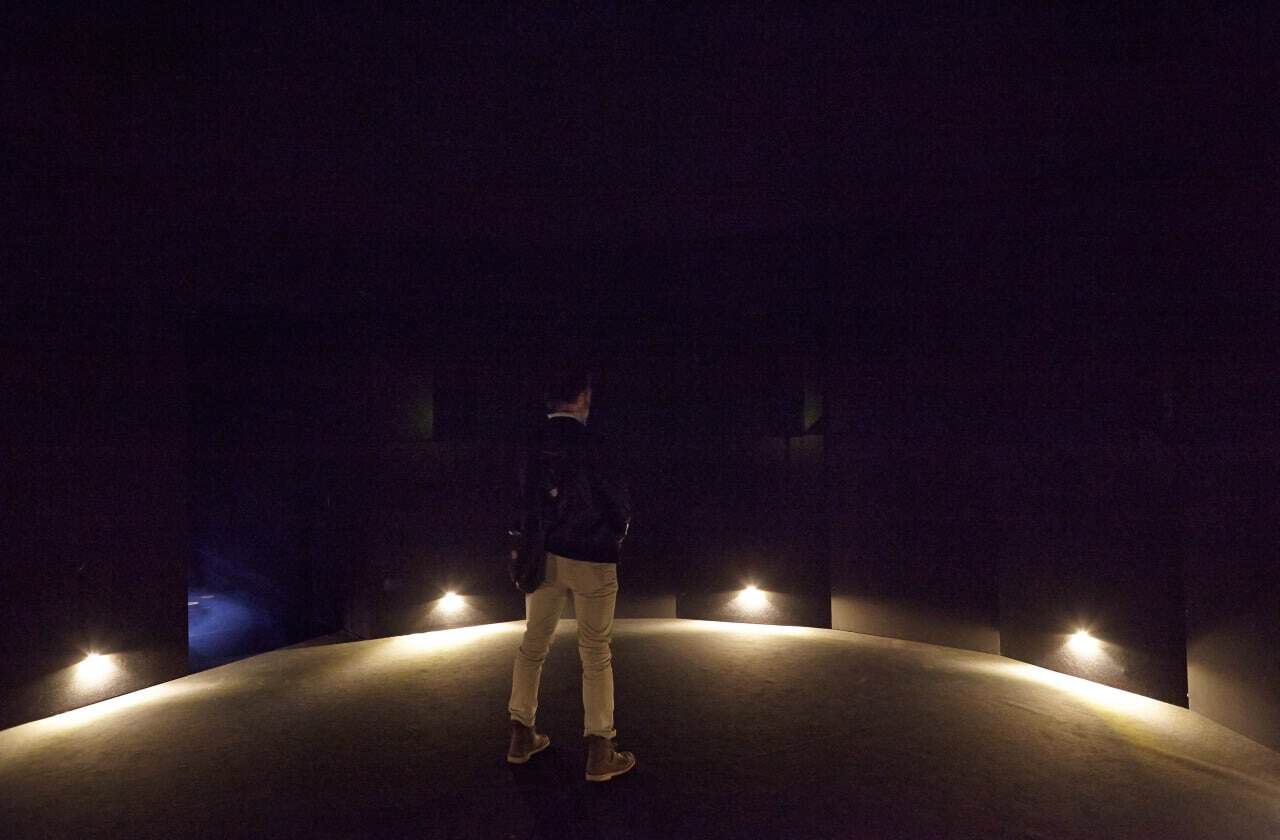 Person standing in dark room with illuminated floor lights at New York Museum.