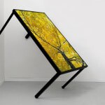 Modern Art Installation With A Tilted Glass Panel Featuring Autumn Tree Artwork.