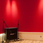 Music Rehearsal Room With Red Walls And Marshall Amplifier On Wooden Floor.