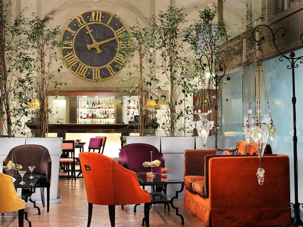 Elegant hotel lounge with vintage decor and large clock at Grand Hotel Continental Siena.