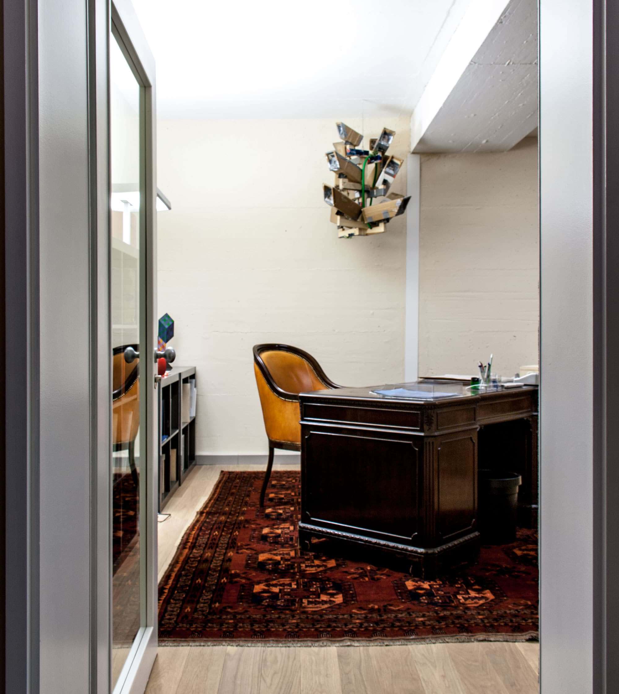 Modern office with wooden desk, leather chair, and unique wall art.