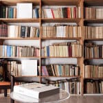 Bookshelf Filled With Vintage Books And A Cozy Armchair In A Library Setting.