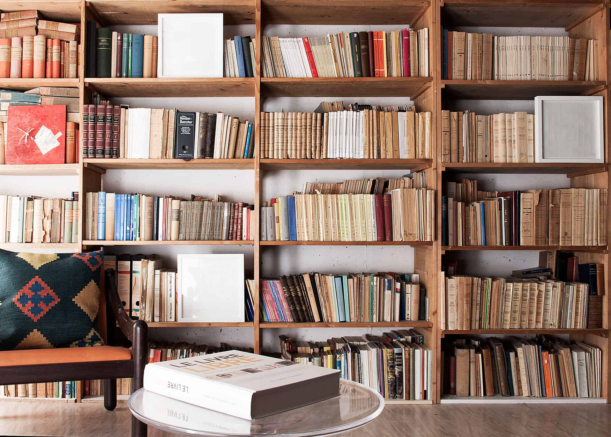 Bookshelf filled with vintage books and a cozy armchair in a library setting.