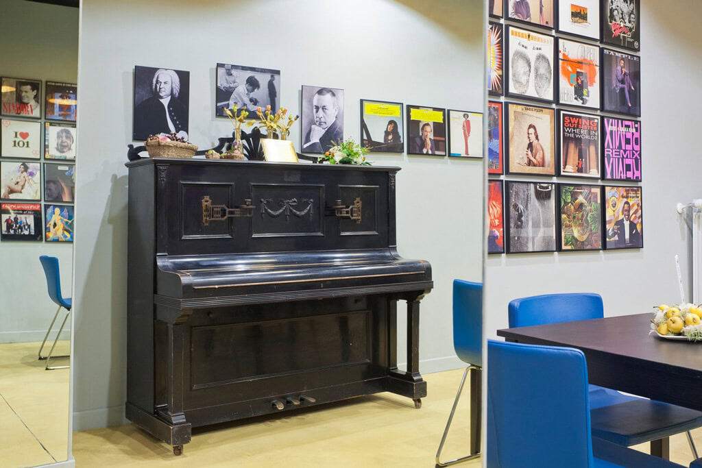 Interior of a modern room with a black piano and colorful wall art.