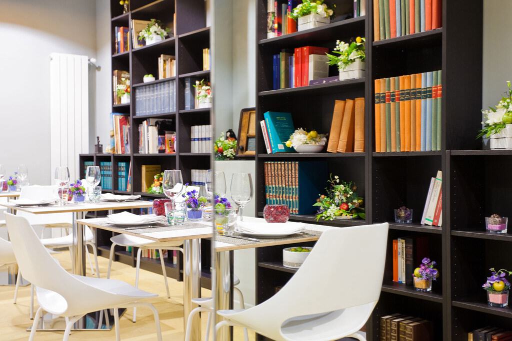 Elegant restaurant interior with bookshelves and table settings for dining.