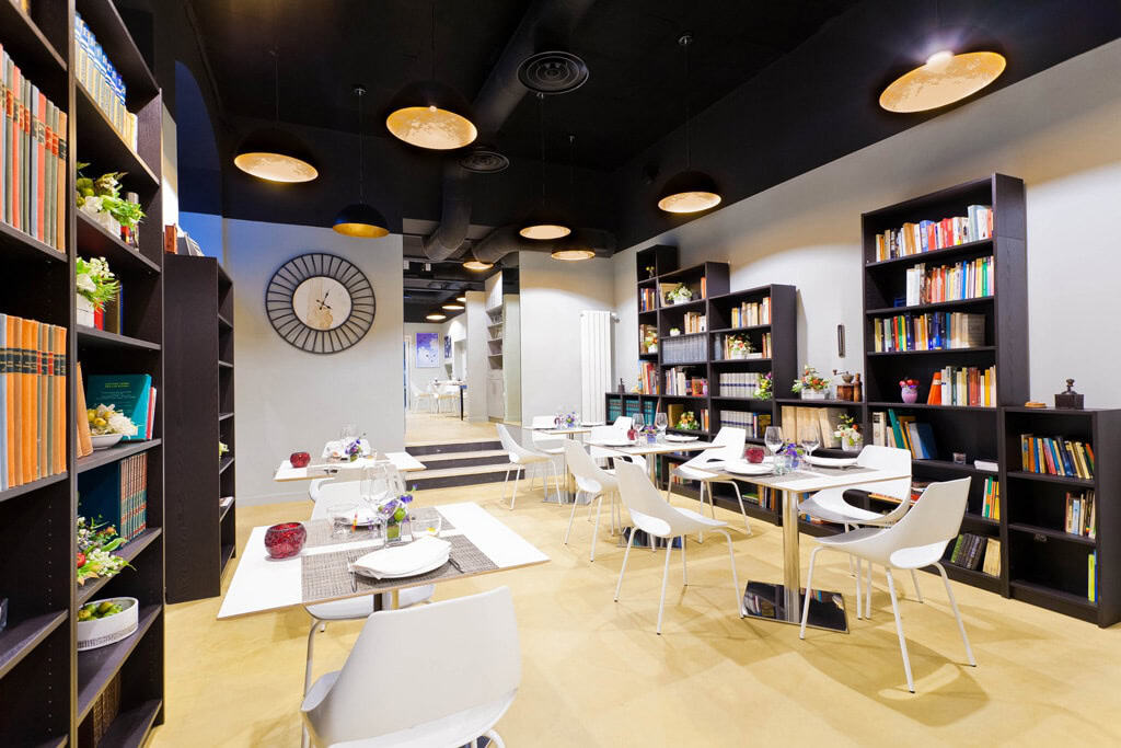 Modern restaurant interior with bookshelves and stylish decor in Milan.