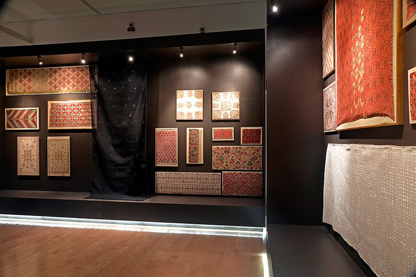 Exhibition of patterned textile samples displayed on black walls at arcHITects srl.